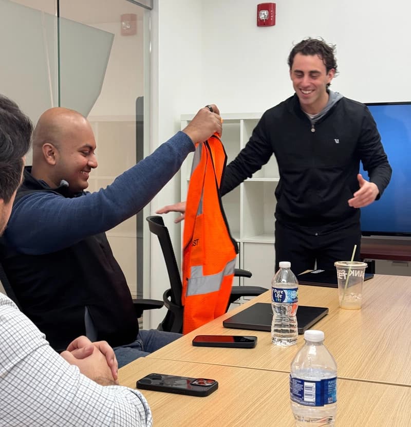 A teammate being handed an orange safety vest